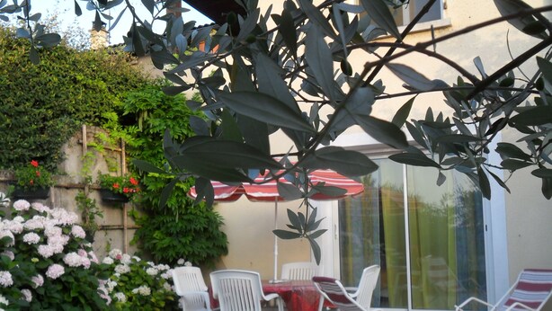 Eine Terrasse mit Tisch und Stühlen, umgeben von Blumentöpfen und Blumen.