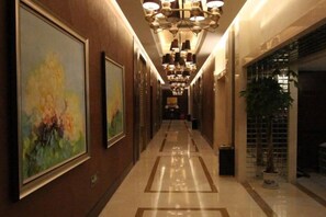Un pasillo de hotel con obras de arte enmarcadas en las paredes, un candelabro y una planta en maceta.
