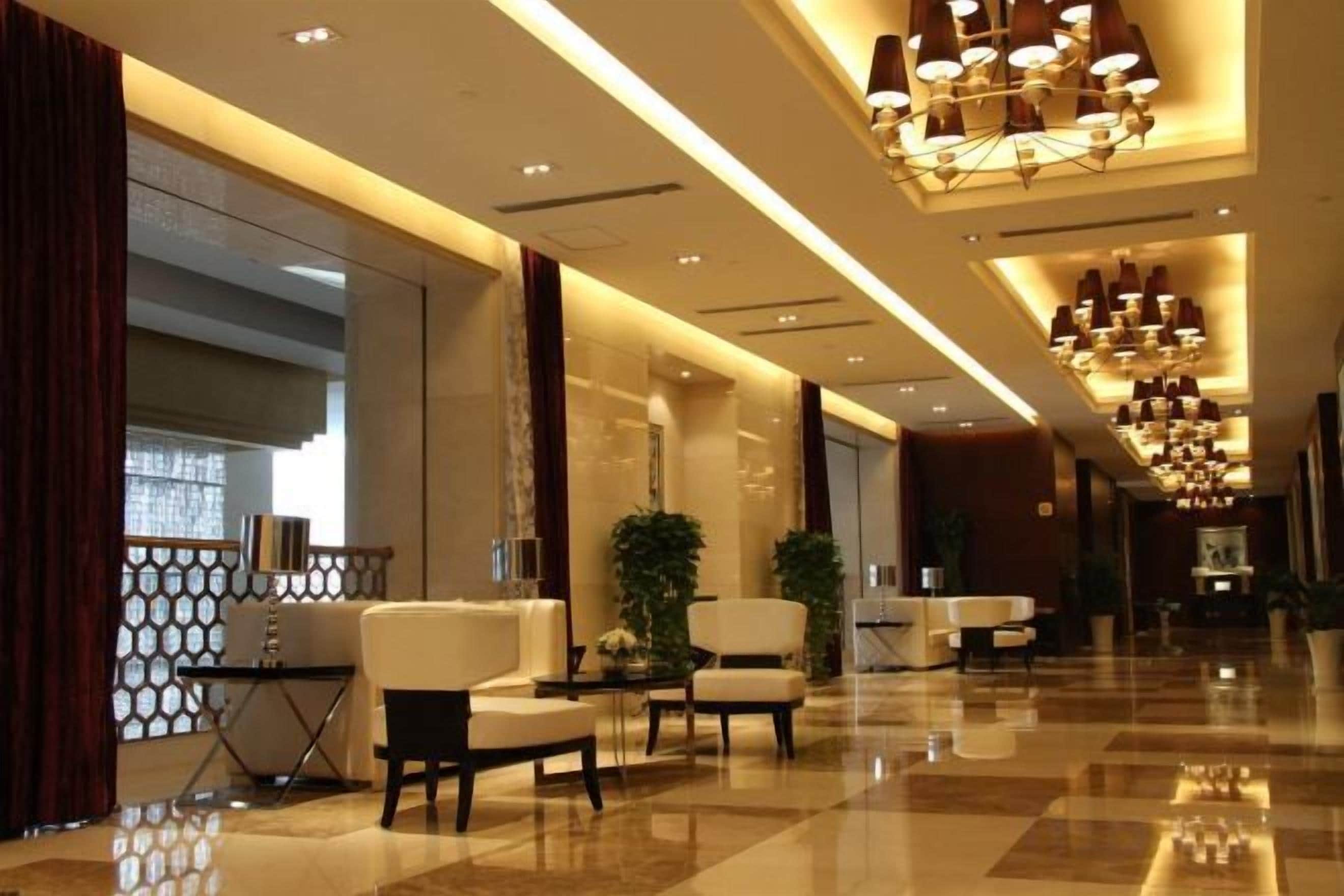 A hotel lobby with a checkered floor, seating area, and a chandelier.