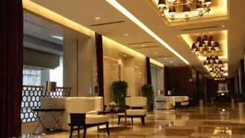 A hotel lobby with a checkered floor, seating area, and a chandelier.