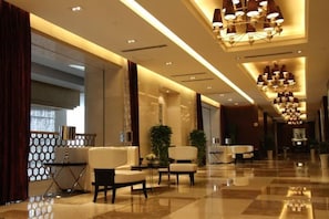 Recepció d'hotel amb sòl de pissos, zona de seients i un penjallum.