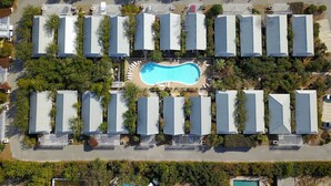 Vista aérea de un resort con varias cabañas dispuestas alrededor de una piscina central.