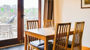 A dining area with a wooden table and chairs, a glass door leading outside, and a framed picture on the wall. - Ground Floor: 
Open plan living space. (Hebden, near Grassington)