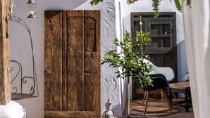 A rustic courtyard with a wooden door, a small statue, and a hanging lantern. - Hotel Rancho Los Lobos (Jimena de la Frontera)