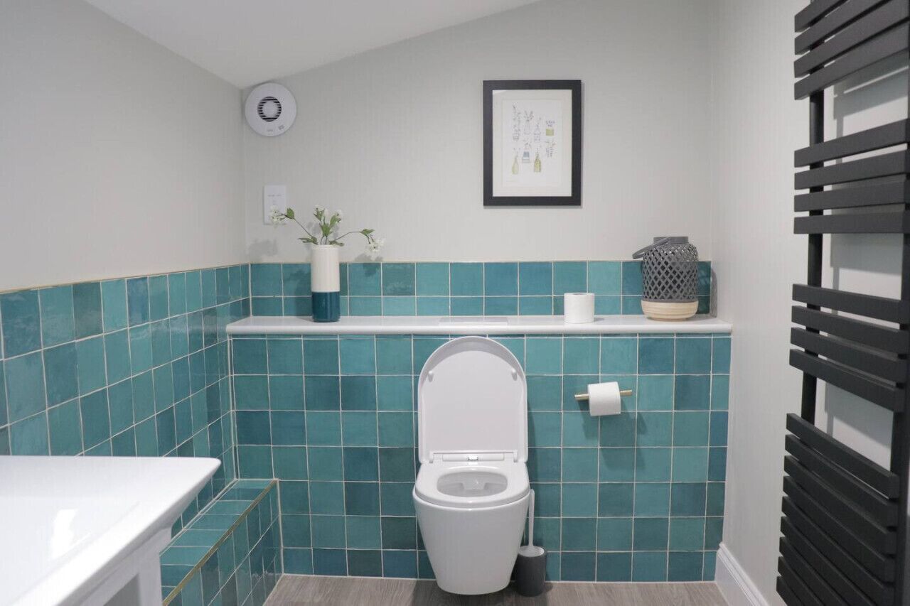 A bathroom with a toilet, a sink, a framed picture on the wall, and a towel holder.