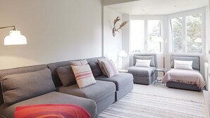 Un salon moderne avec un canapé gris, un plaid rouge et un tapis à rayures.