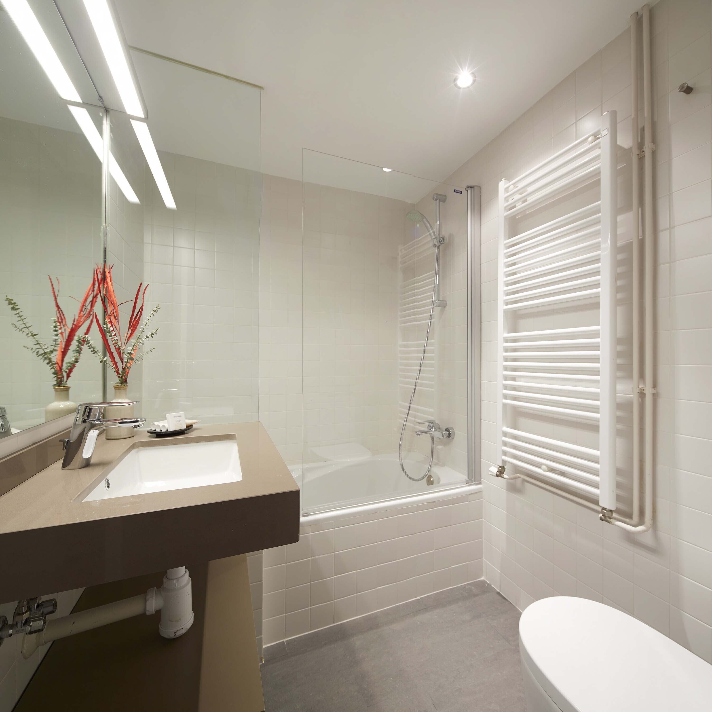 A modern bathroom with a glass-enclosed shower, a bathtub, a toilet, and a vanity with a sink and mirror.
