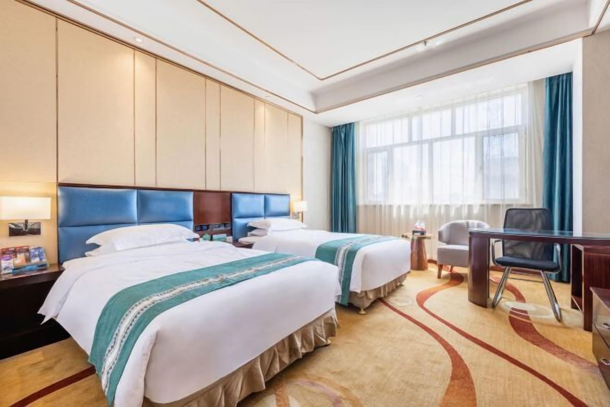 Una habitación de hotel con dos camas, un escritorio y una silla.
