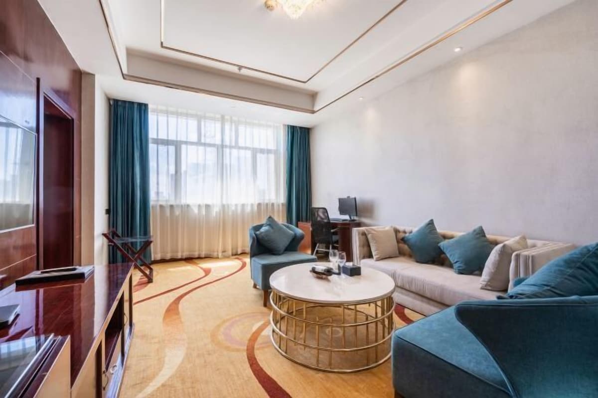 Una sala de estar moderna con sofá, sillones, una mesa de centro y televisión.