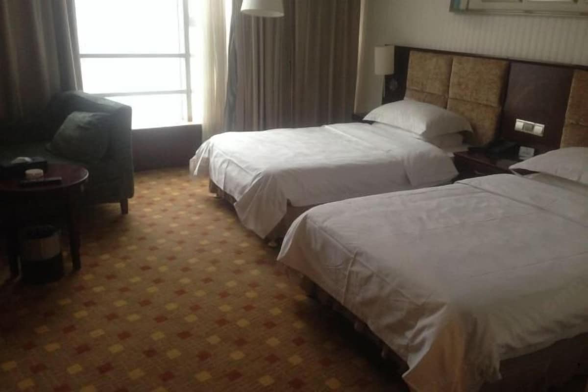 Habitación de hotel con dos camas, un escritorio pequeño, una silla y una alfombra estampada.