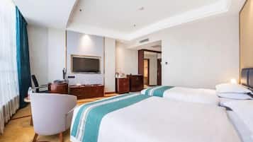A hotel room with a large bed, a desk, a chair, a TV, and a wardrobe.