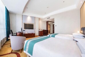 Habitación de hotel con una cama grande, un escritorio, una silla, un televisor y un armario.