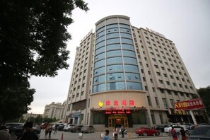 A multi-story hotel with a curved facade, a prominent entrance, and several visible windows. - Hualong Hotel (Aksu City)