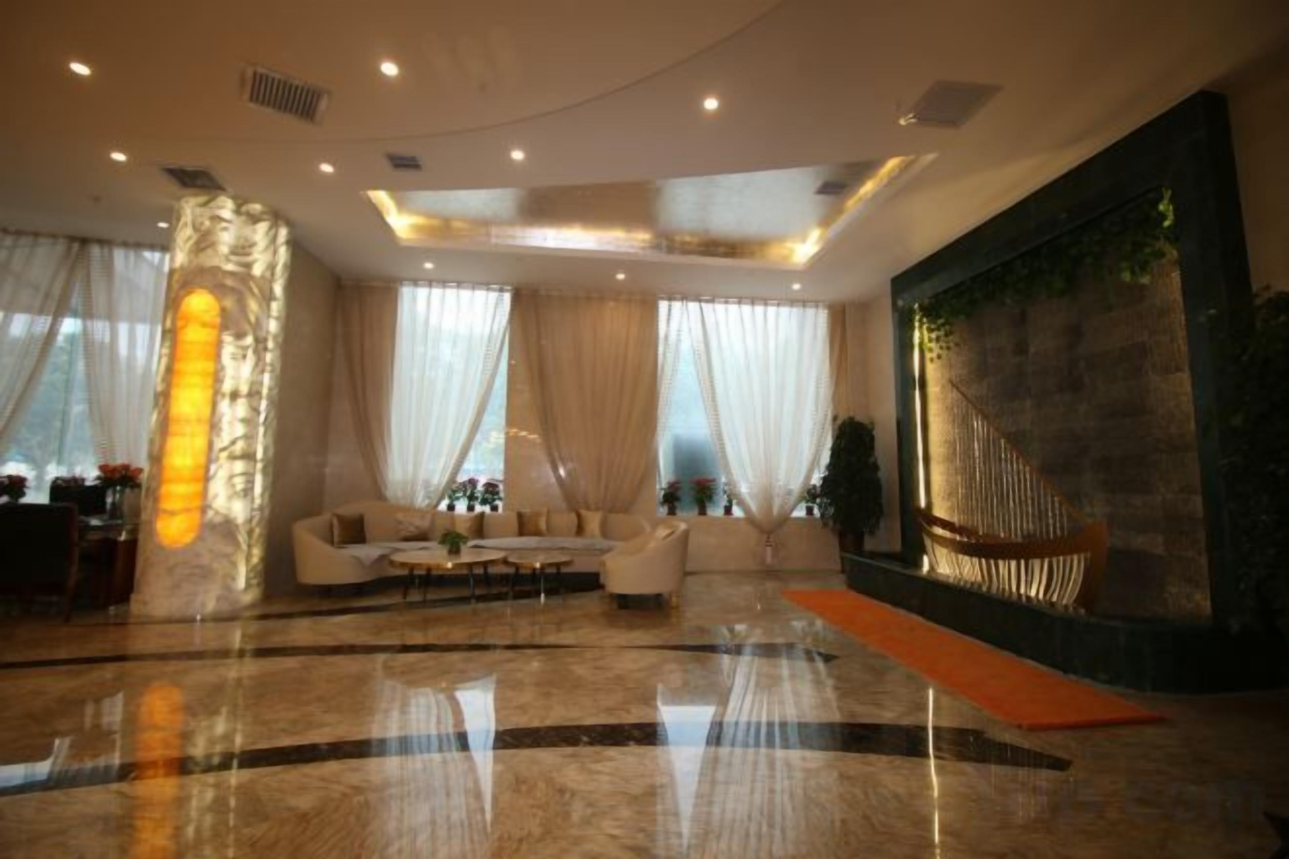 A spacious lobby with a marble floor, a seating area with sofas, and a large wall with a textured design.