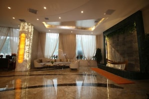 A spacious lobby with a marble floor, a seating area with sofas, and a large wall with a textured design.