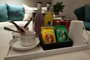 Una bandeja con una taza, botellas y bocadillos empacados sobre una mesa.