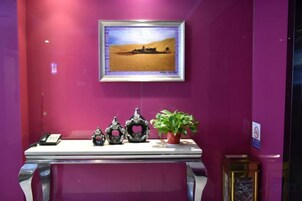 A room with a table displaying decorative items, a framed picture on the wall, and a potted plant.