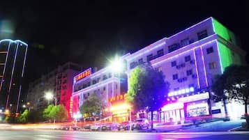 A multi-story building with illuminated signage and a street view at night.