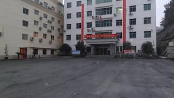 A building with multiple floors, a red banner, and a paved ground in front.