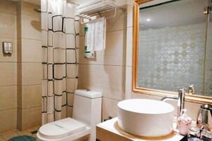 Un baño con inodoro, lavamanos, cortina de ducha y espejo.