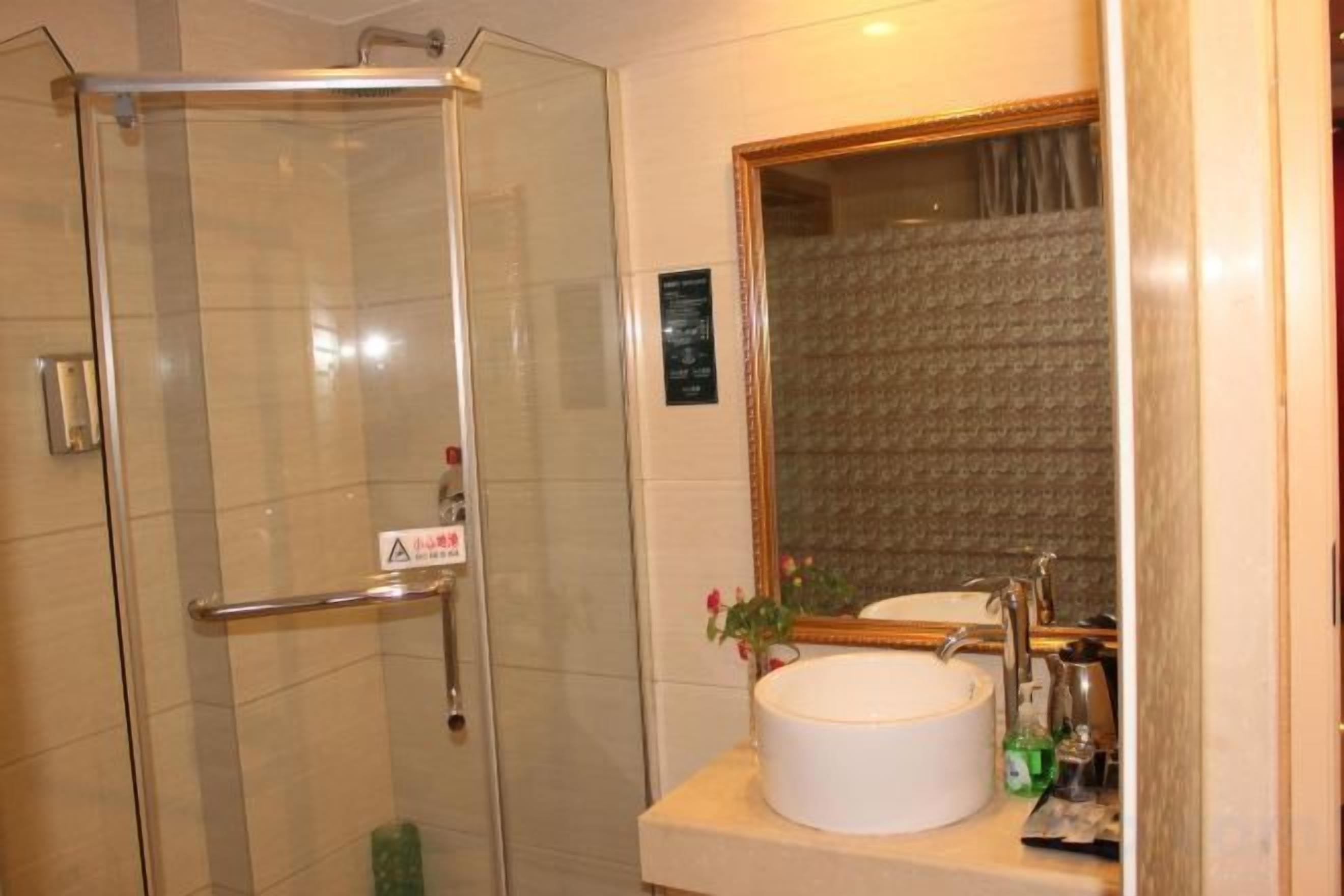 Un baño con cabina de ducha de vidrio, lavabo con espejo y barra para toallas.