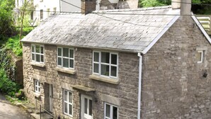Una casa in pietra con tetto spiovente, diverse finestre e un piccolo portico.