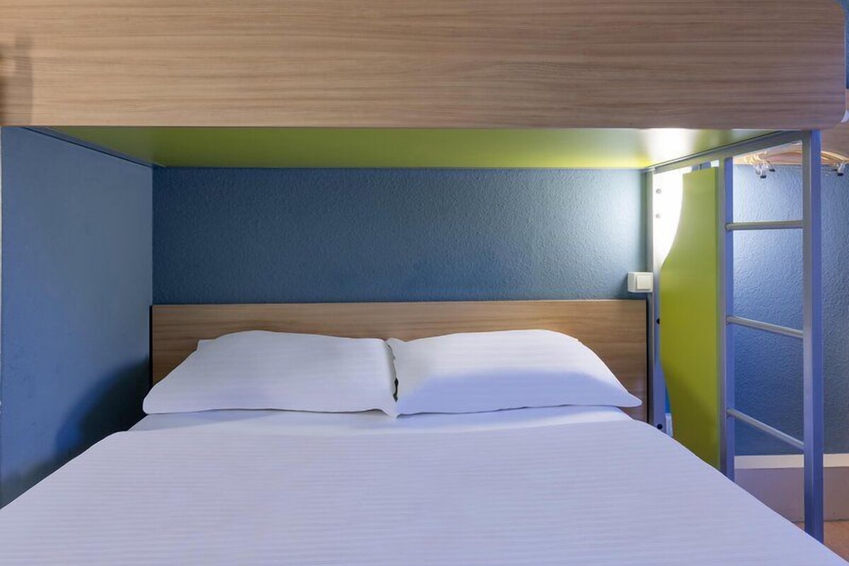 Un lit superposé avec une tête de lit en bois, une literie blanche et un mur d’accent vert.