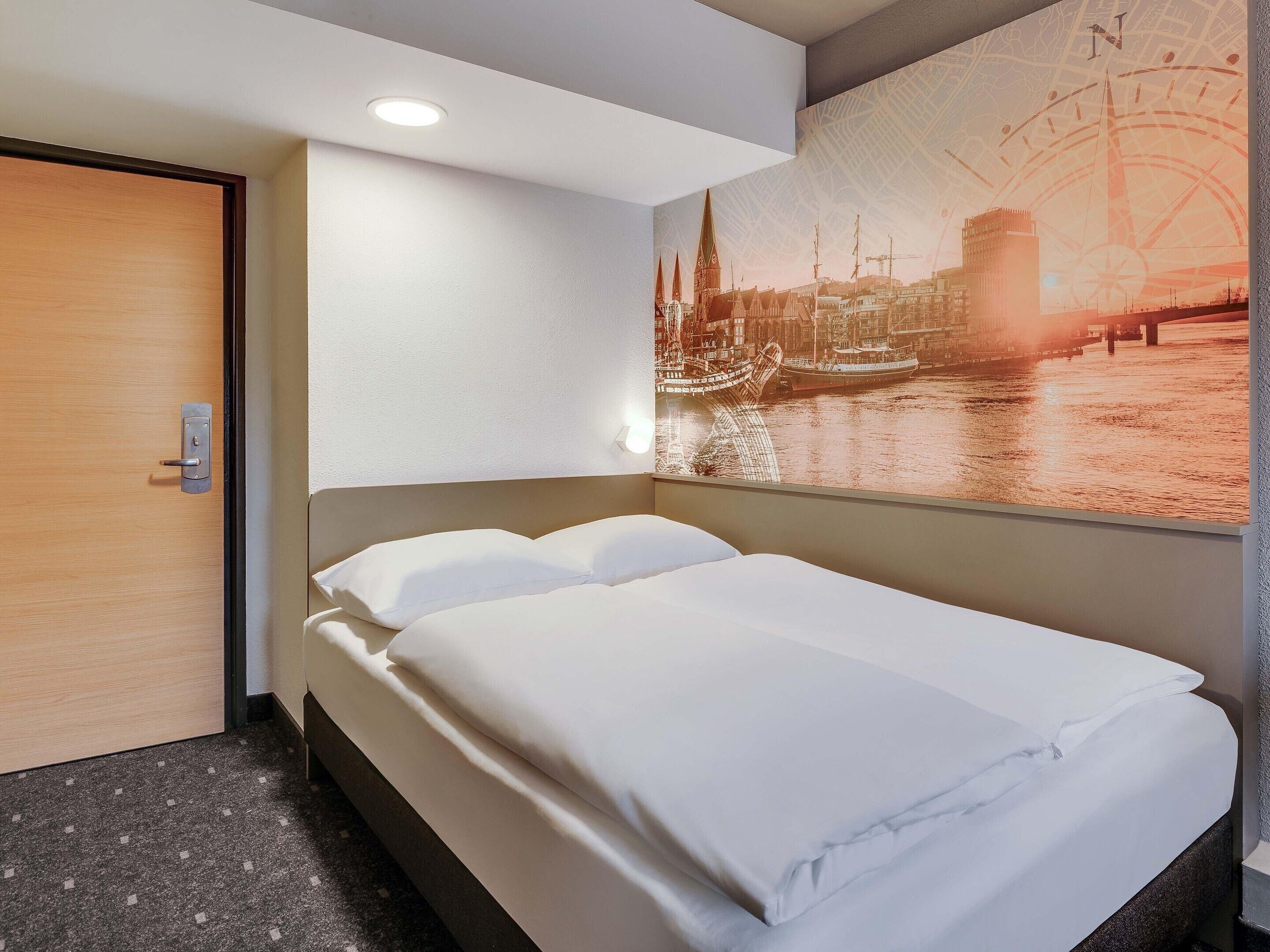 Ein Hotelzimmer mit Bett, Tür und einer Wand mit Stadtbild-Fresko.