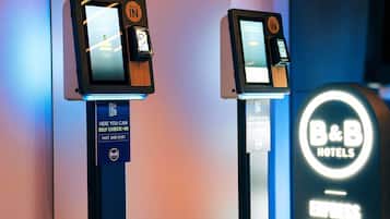 Dos quioscos de auto check-in en B&B Hotels, con un cartel que indica 'Pago Express'.