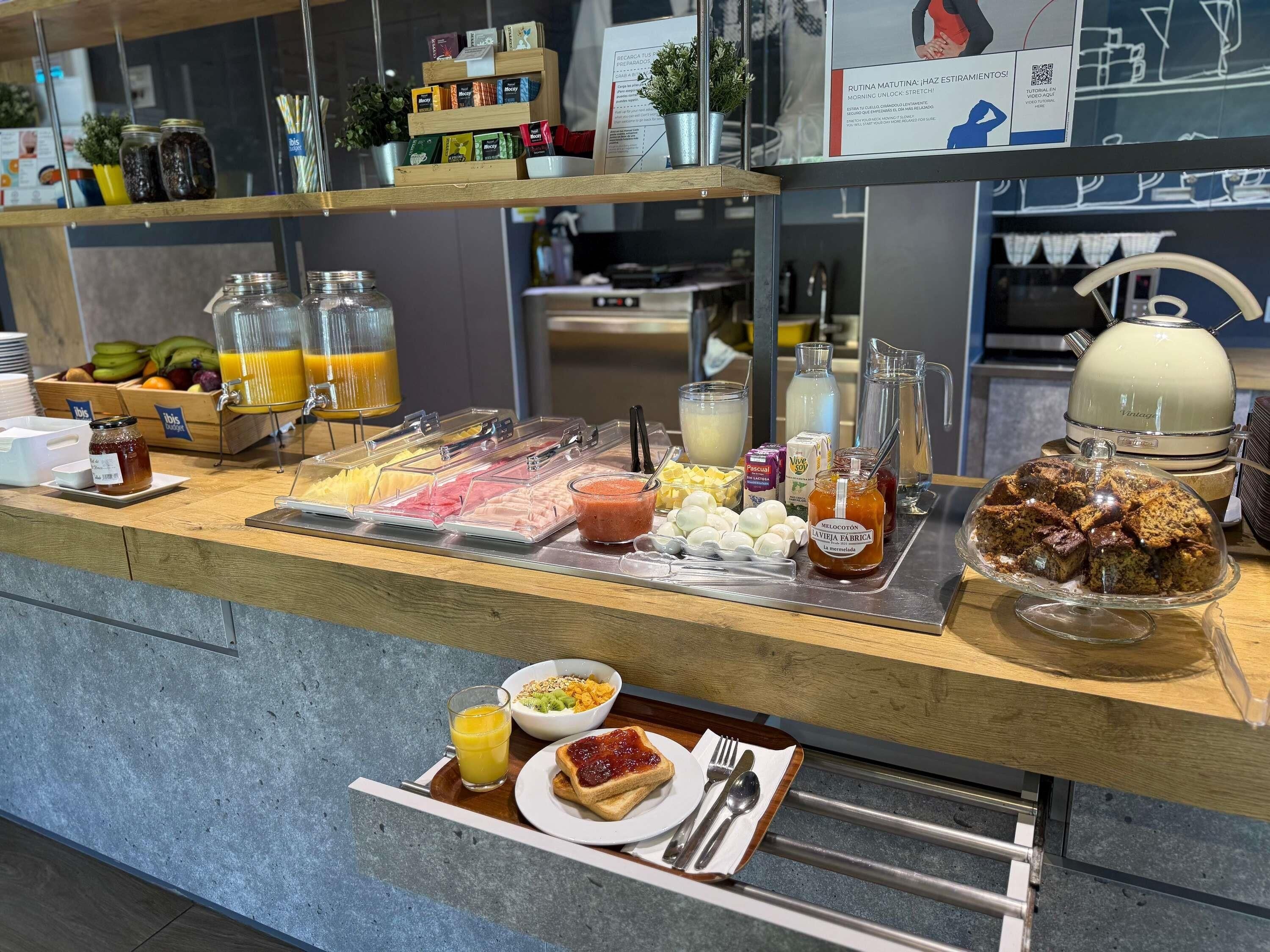 Un bufé de desayuno con diversas opciones de comida, una máquina de café y un dispensador de jugo.