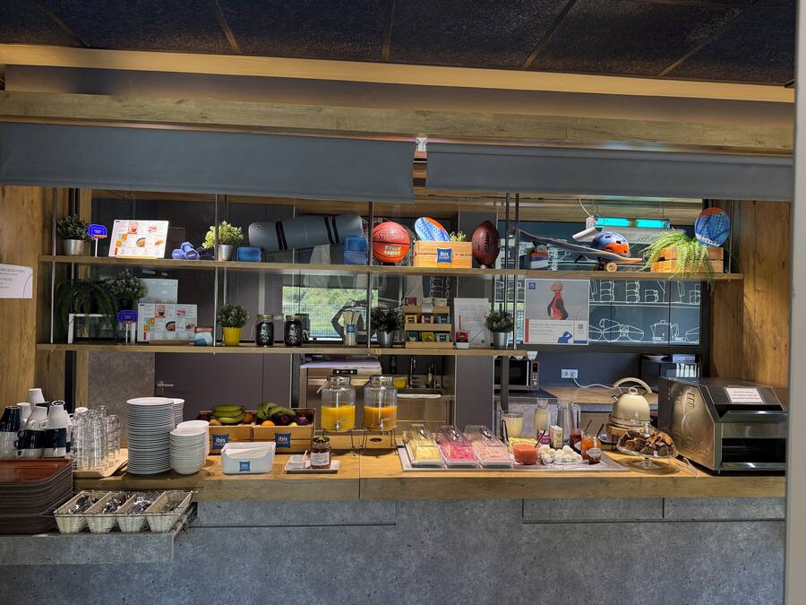 Una barra de desayuno con diversos alimentos, una máquina de café y un menú en una pizarra.