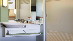A modern bathroom with a large mirror, a sink, and a towel rack. - Ibis Budget Valencia Alcasser (Silla)