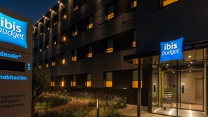 A modern building with 'ibis budget' signage, a landscaped garden area, and a glass entrance. - Ibis Budget Valencia Alcasser (Silla)