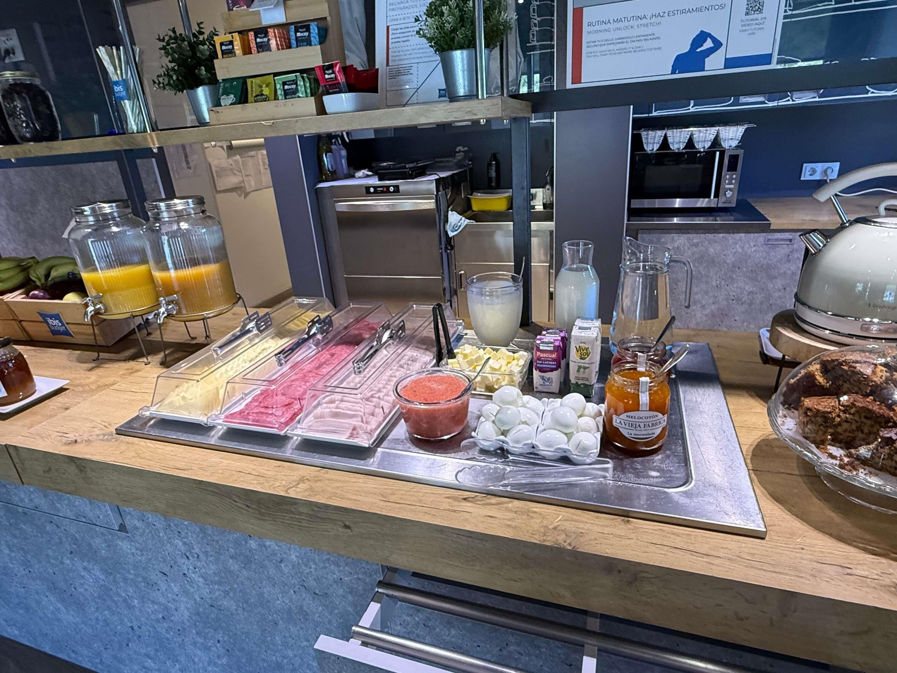 A buffet counter with various food items, including a selection of juices, dairy products, and pastries.