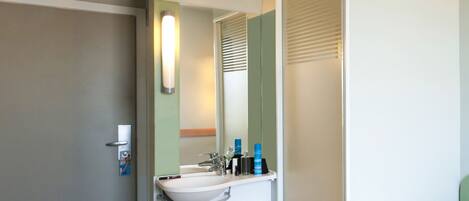 A modern bathroom with a sink, mirror, and towel rack.