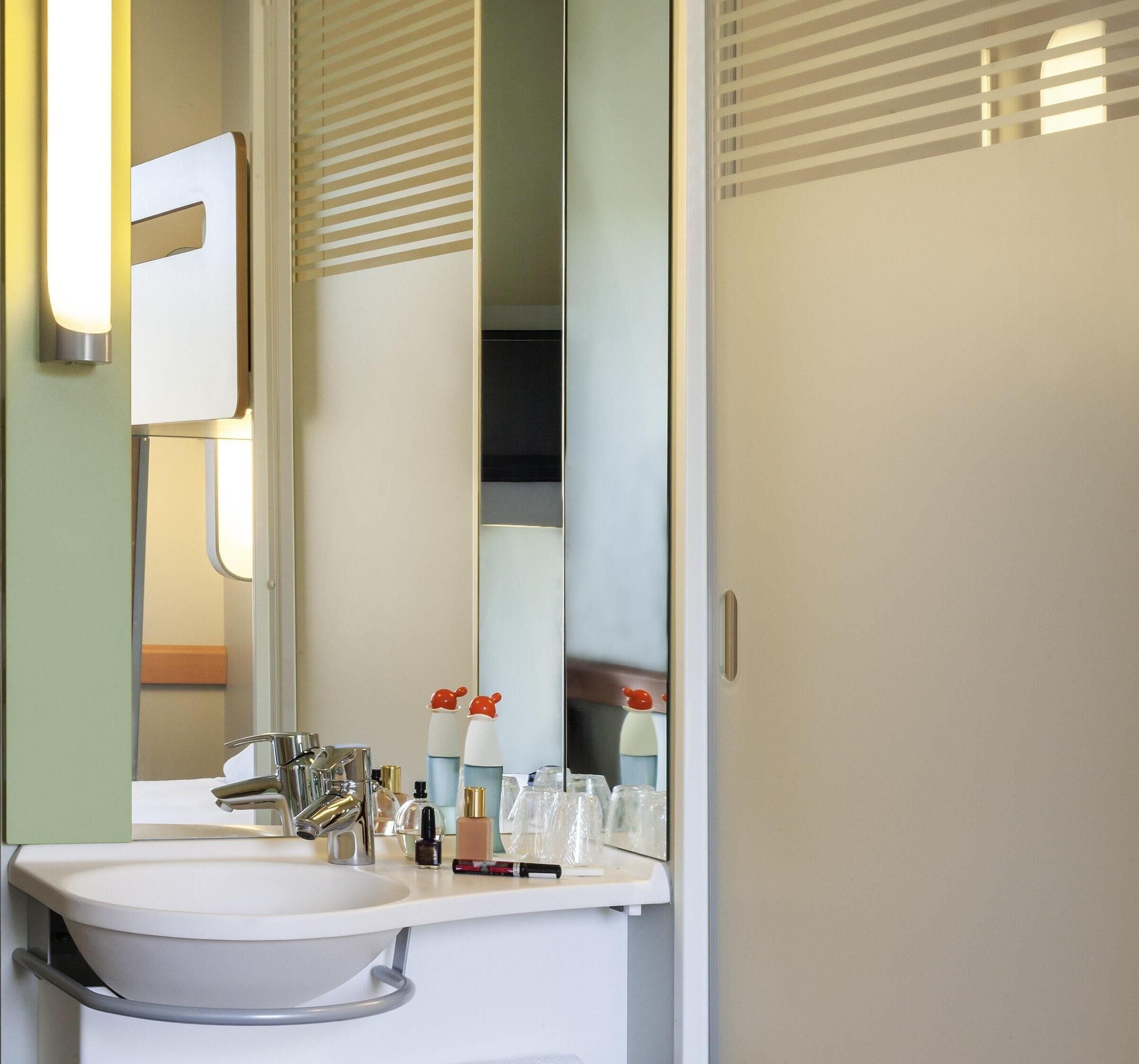 A bathroom with a sink, mirror, and toiletries.