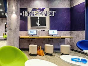 Een moderne werkruimte met twee computers, een groot bord met 'INTERNET' erop en kleurrijke zitplaatsen.