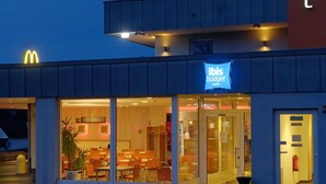 A hotel with a McDonald's sign, a blue 'ibis budget' sign, and a glass facade with interior seating. - Ibis Budget Bonn Süd Königswinter (Königswinter)
