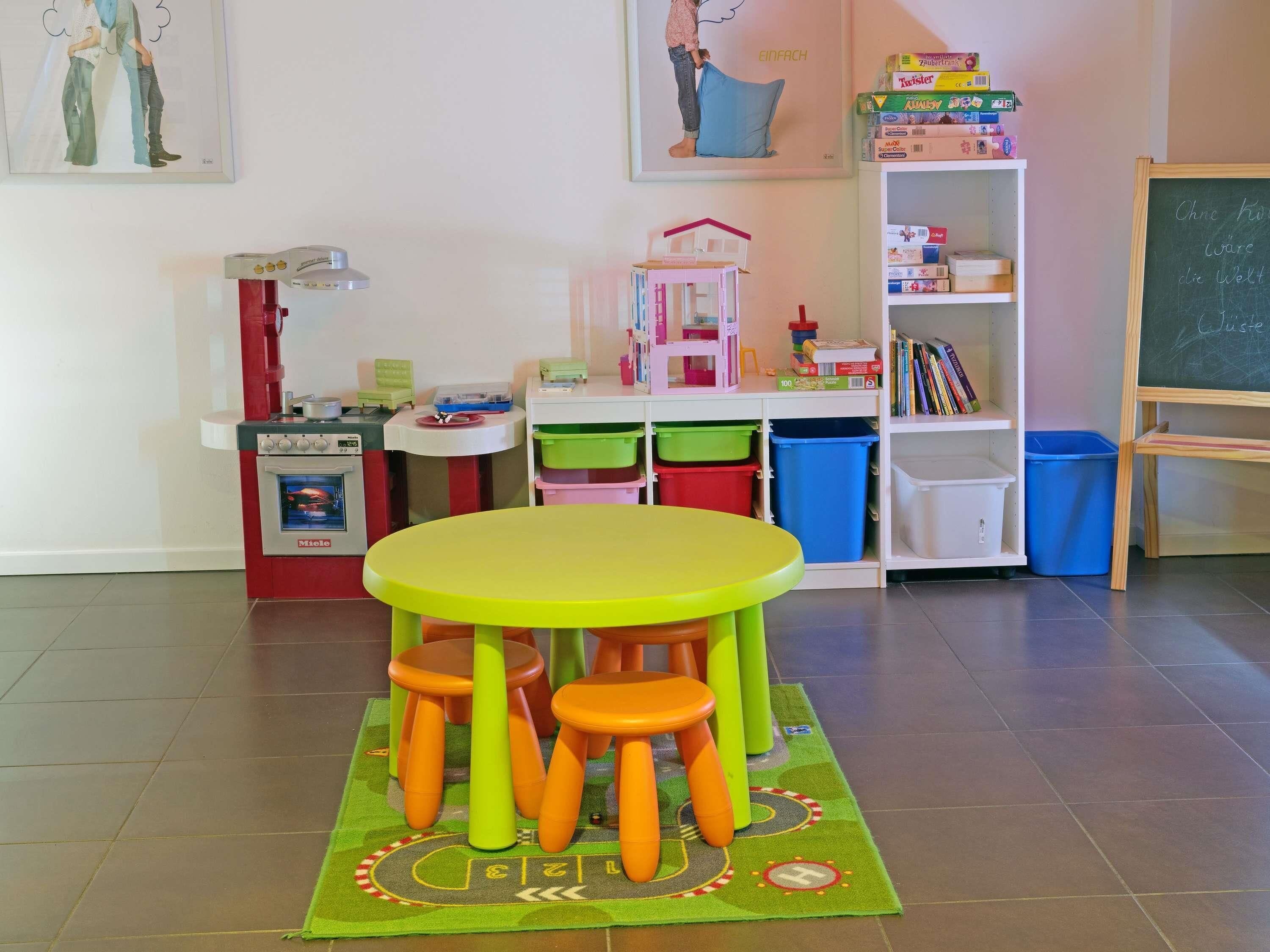 A children's play area with a table, chairs, and storage bins.