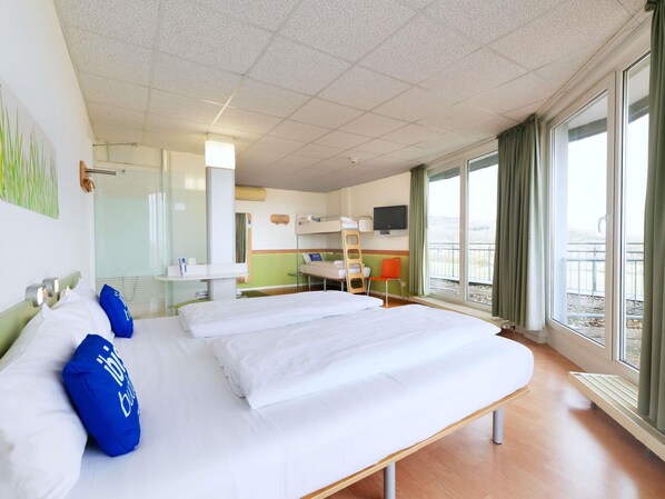 Una habitación de hotel con una cama grande, un escritorio, televisión y un balcón con vistas.
