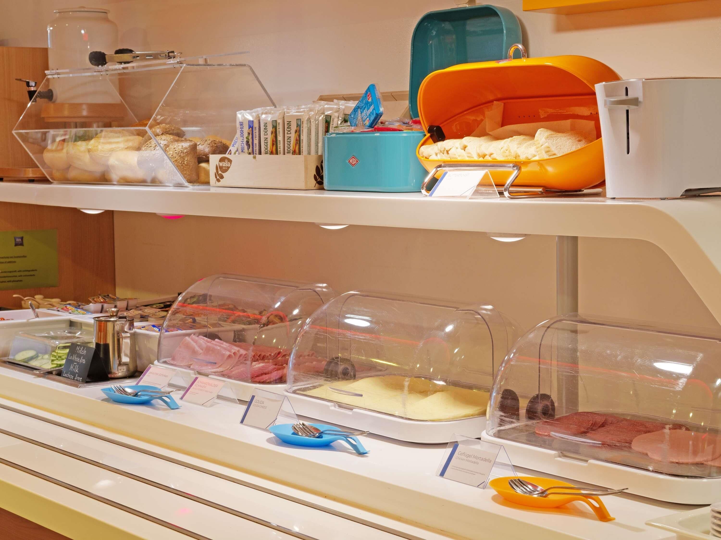 A buffet with various food items in clear containers, utensils, and a coffee station.
