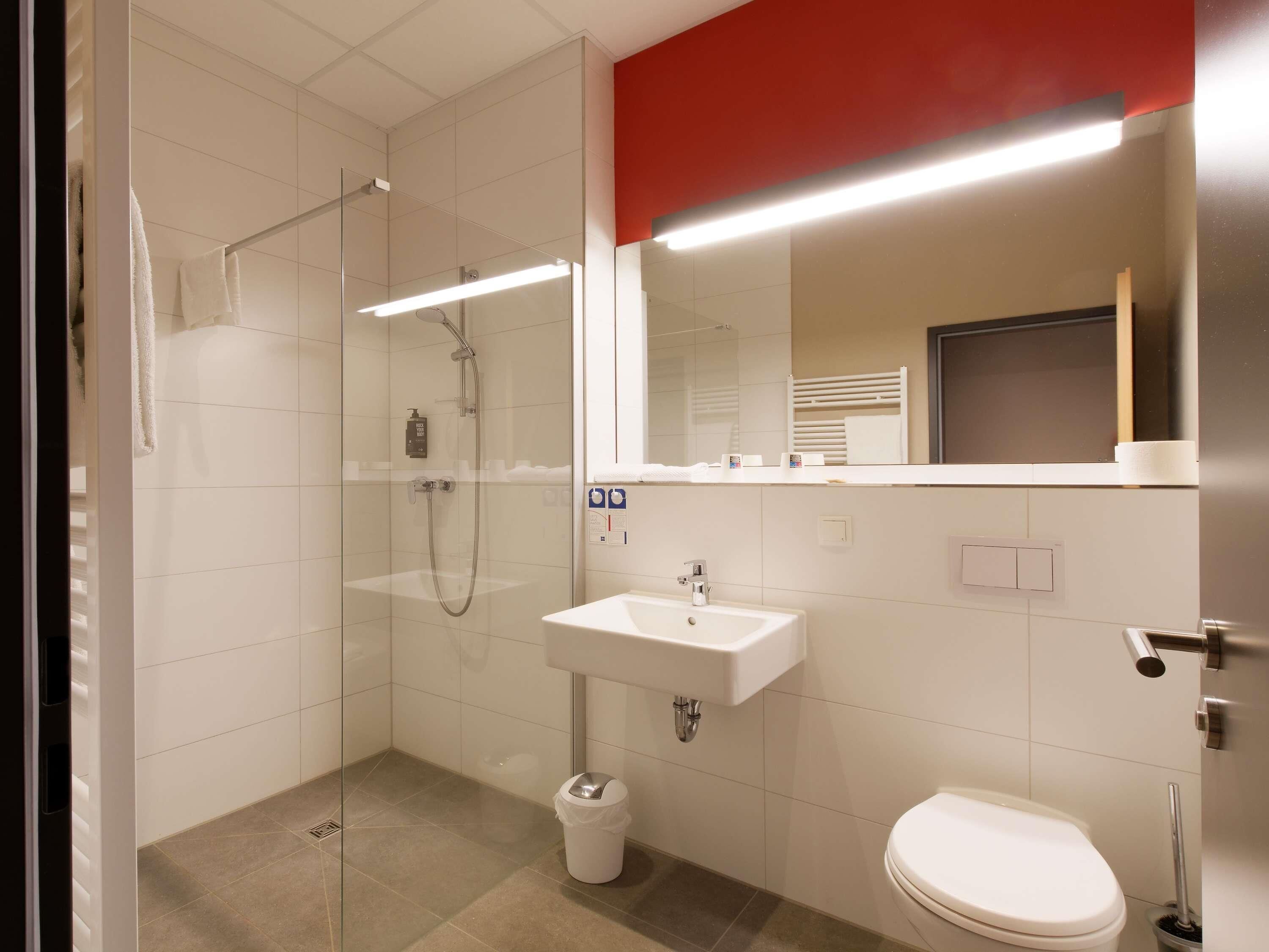 Un baño moderno con ducha envuelta en vidrio, un lavabo blanco y un inodoro.