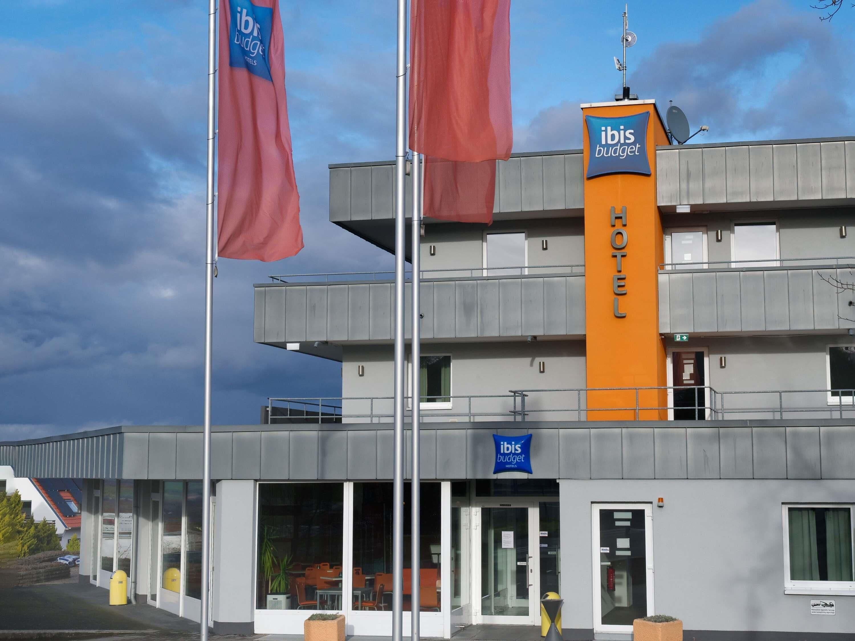 Un hotel moderno con un llamativo letrero de 'ibis budget', varios pisos y un cielo despejado.