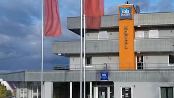 Un hotel moderno con un llamativo letrero de 'ibis budget', varios pisos y un cielo despejado.