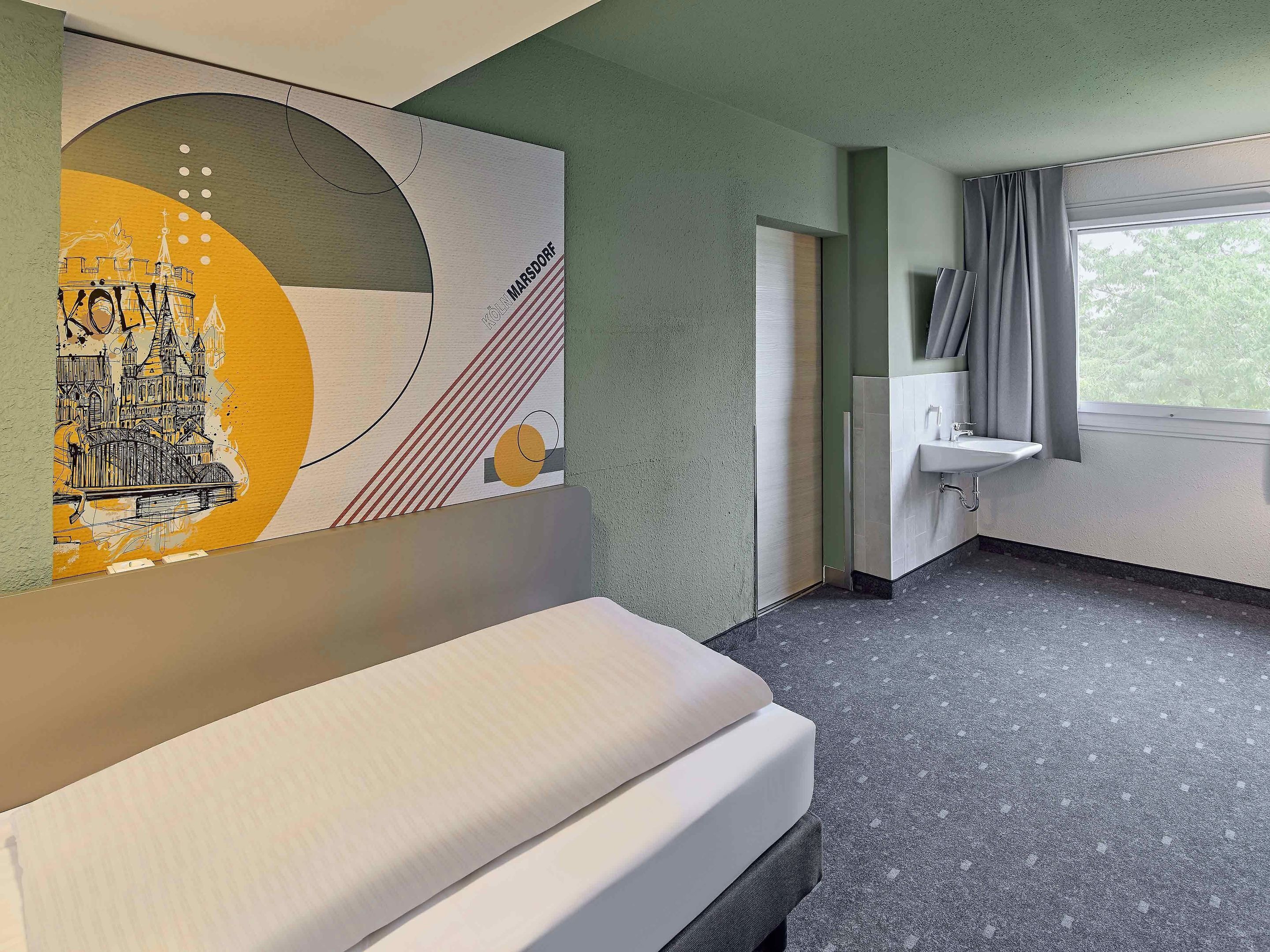 Una habitación de hotel con una cama, un lavamanos y un cuadro abstracto grande en la pared.