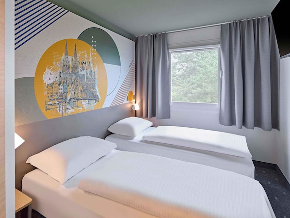 Une chambre d’hôtel avec deux lits, une grande fenêtre avec des rideaux, une fresque murale et une lampe de chevet.