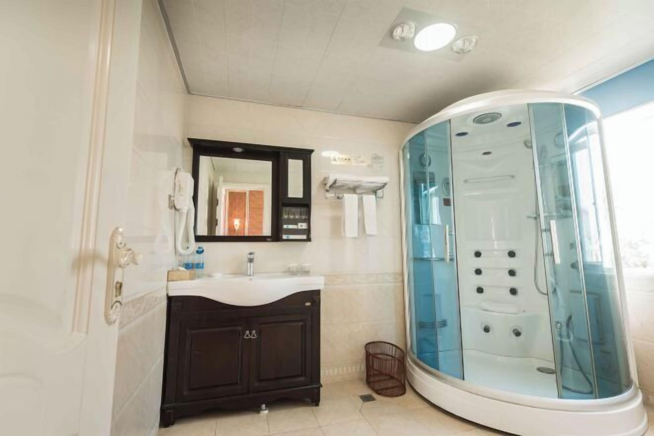 A modern bathroom with a glass-enclosed shower, a dark wooden vanity, and a white sink.