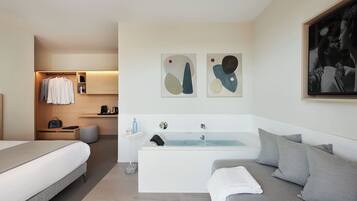 Una habitación de hotel moderna con cama, sofá, bañera y arte abstracto en la pared.