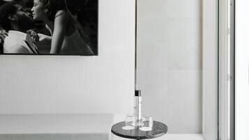 A modern bathroom with a large mirror, a sink, and a small round table with glasses.