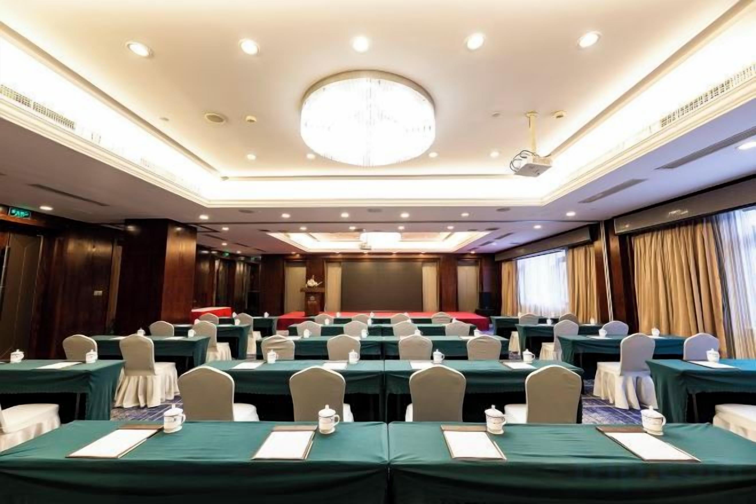 Ein Konferenzraum mit Tischen, Stühlen und einer Bühne.